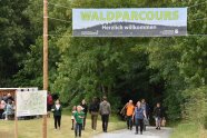 Unter dem Eingangsbanner gehen Besucher des Frankenwaldtages zum Waldparcours